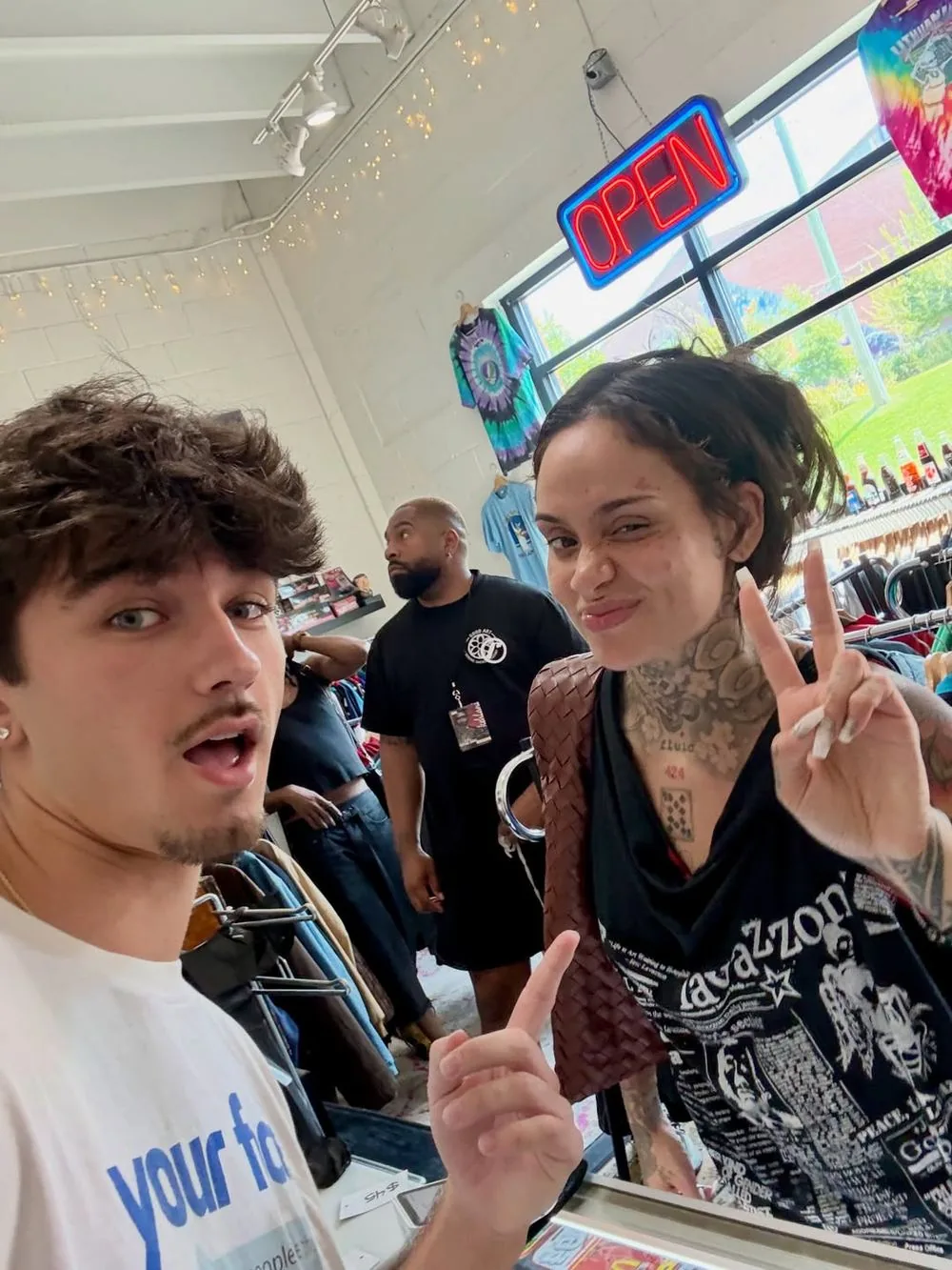 Kehlani and the EVOKE owner in the shop under the neon Open sign