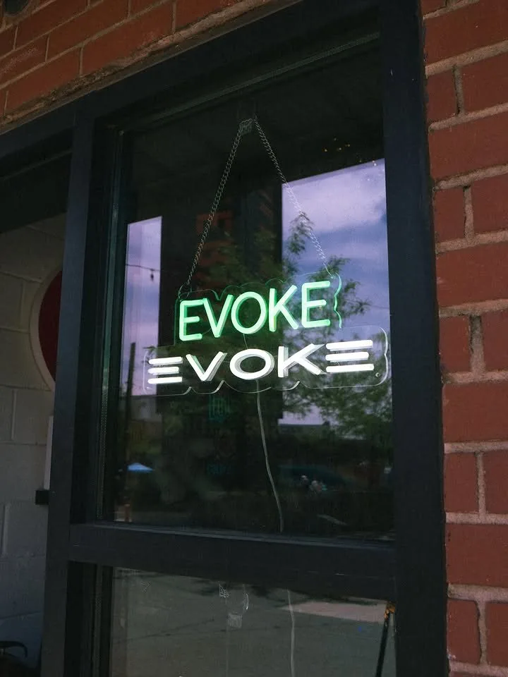 The EVOKE neon sign hanging in the shop window
